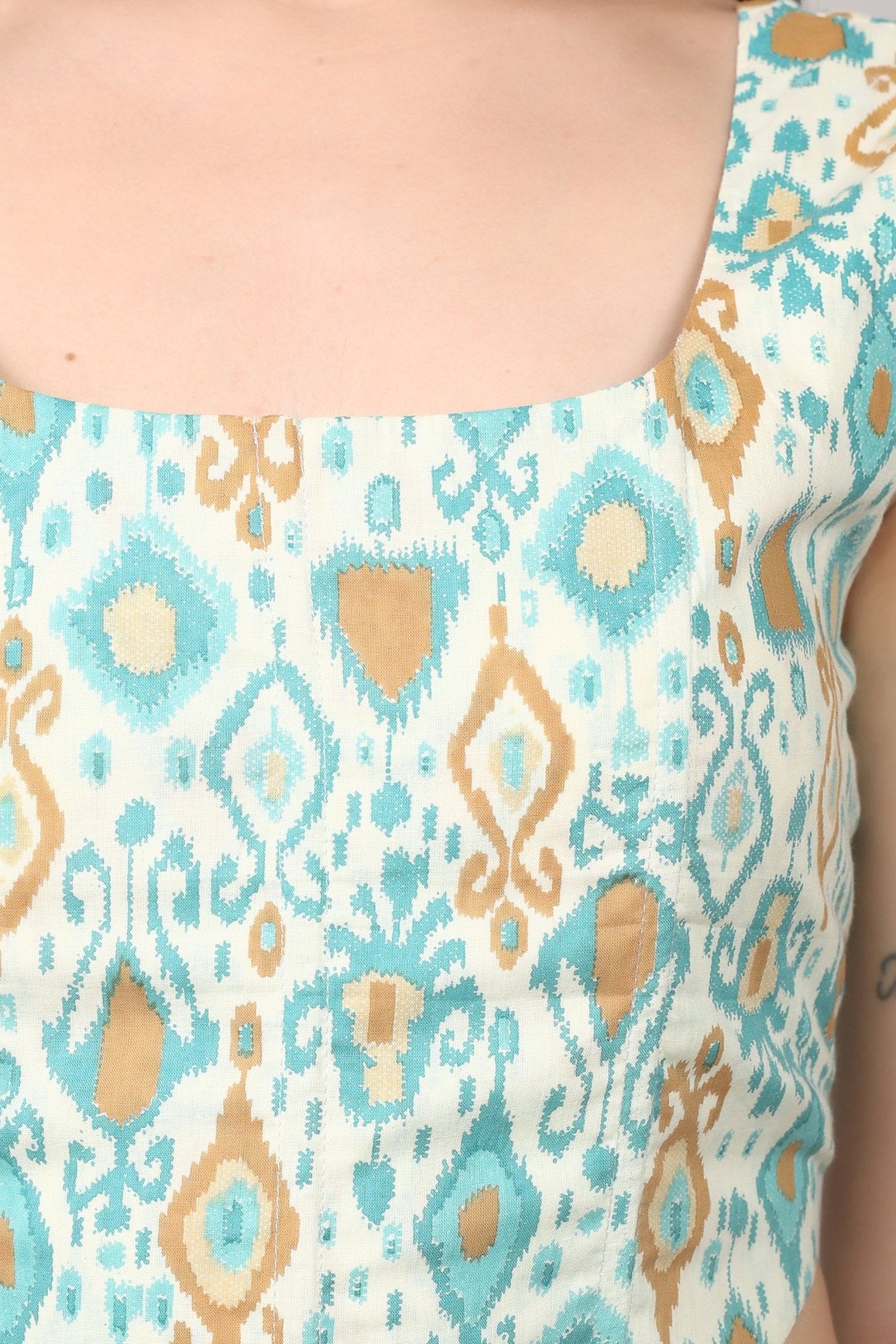 Sleeveless cream corset top with aqua blue and mustard ikat print, square neckline, deep U back, and fitted waist in cotton fabric