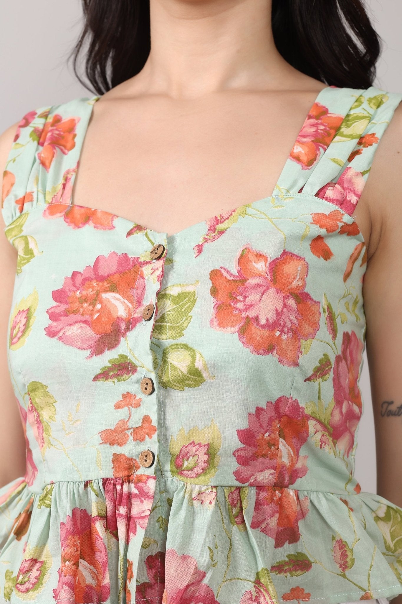 Sleeveless mint green 100% cotton peplum top with vibrant pink and orange floral print, wide straps, sweetheart neckline, button-down front, and ruffled hem
