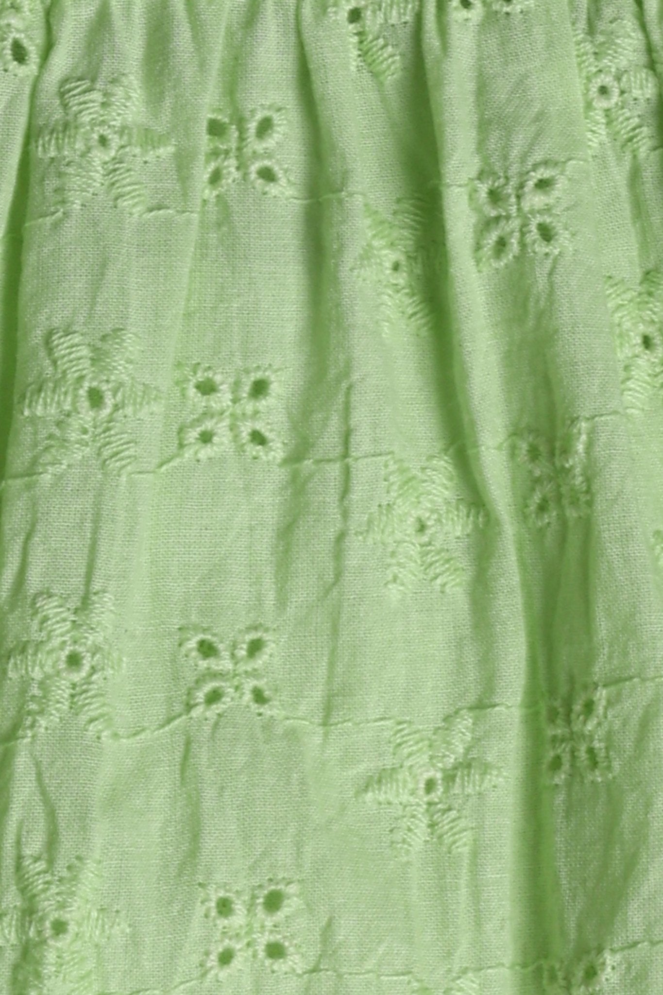 Lime green 100% Schiffli cotton wrap-style top with V-neckline, flutter cap sleeves, flared mid-hip hem, scalloped edging, relaxed fit.