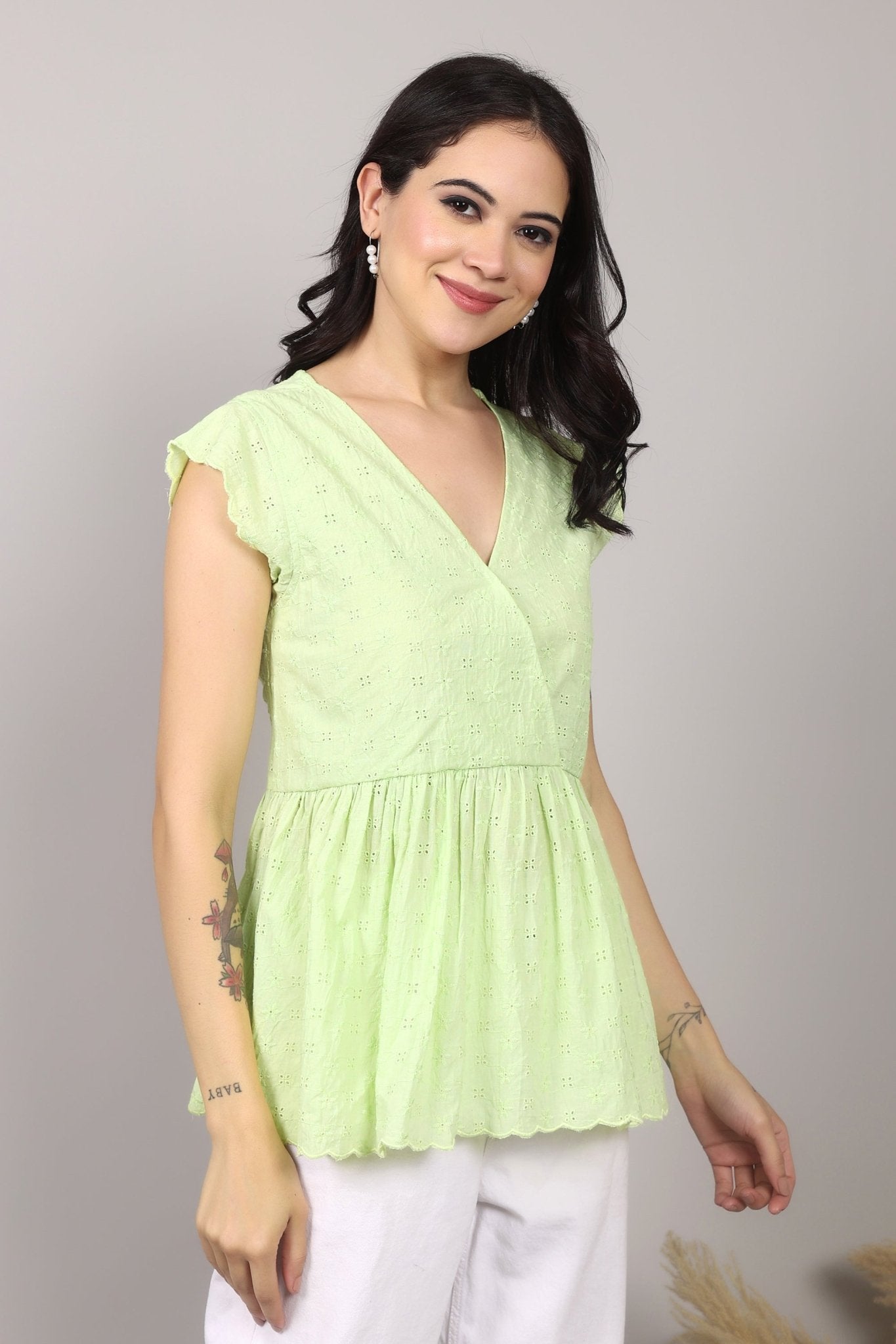 Lime green 100% Schiffli cotton wrap-style top with V-neckline, flutter cap sleeves, flared mid-hip hem, scalloped edging, relaxed fit.