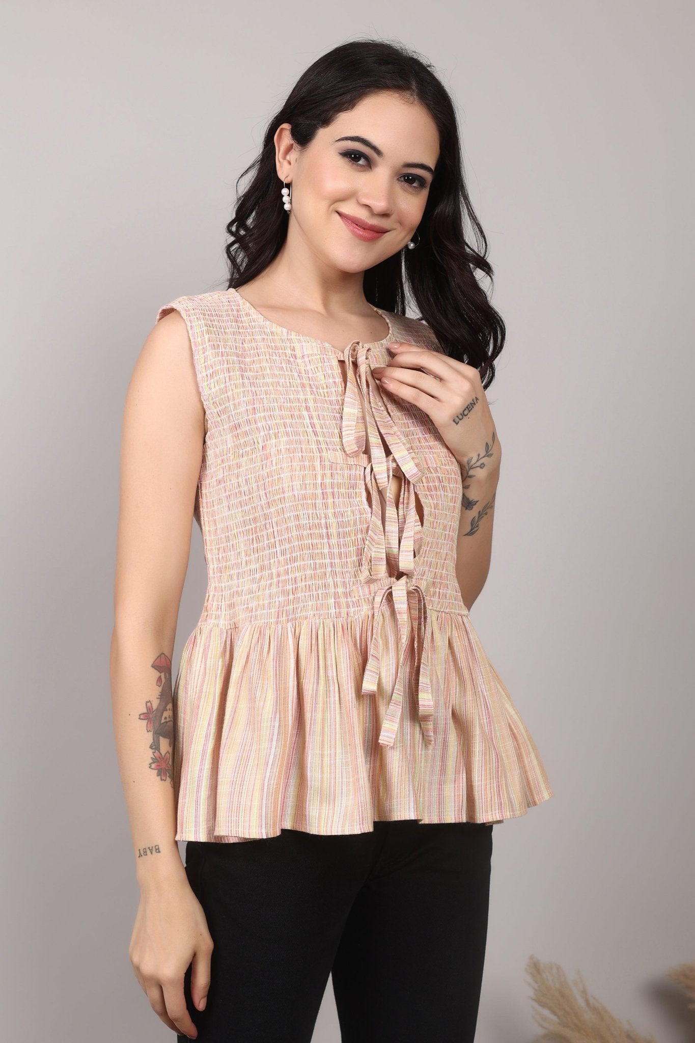 Beige sleeveless cotton-blend top with multicolor striped weave, smocked bodice, triple-tie front keyhole, and flared peplum hem—relaxed and breezy.