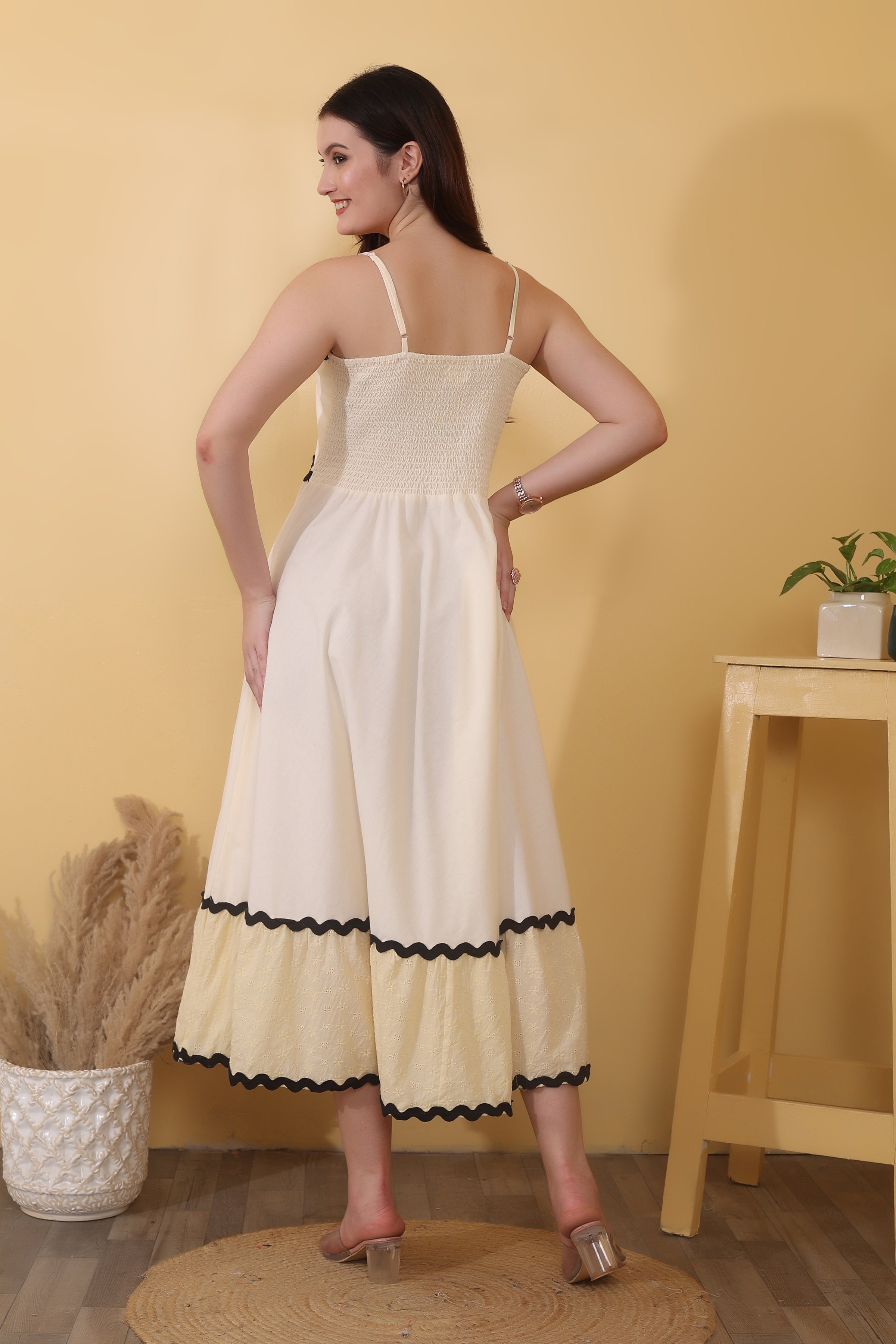 Cream maxi dress crafted from 100% cotton poplin with Schiffli cotton tiers, featuring a straight neckline with adjustable spaghetti straps, smocked back, tiered hem, and bold black ric-rac trim.